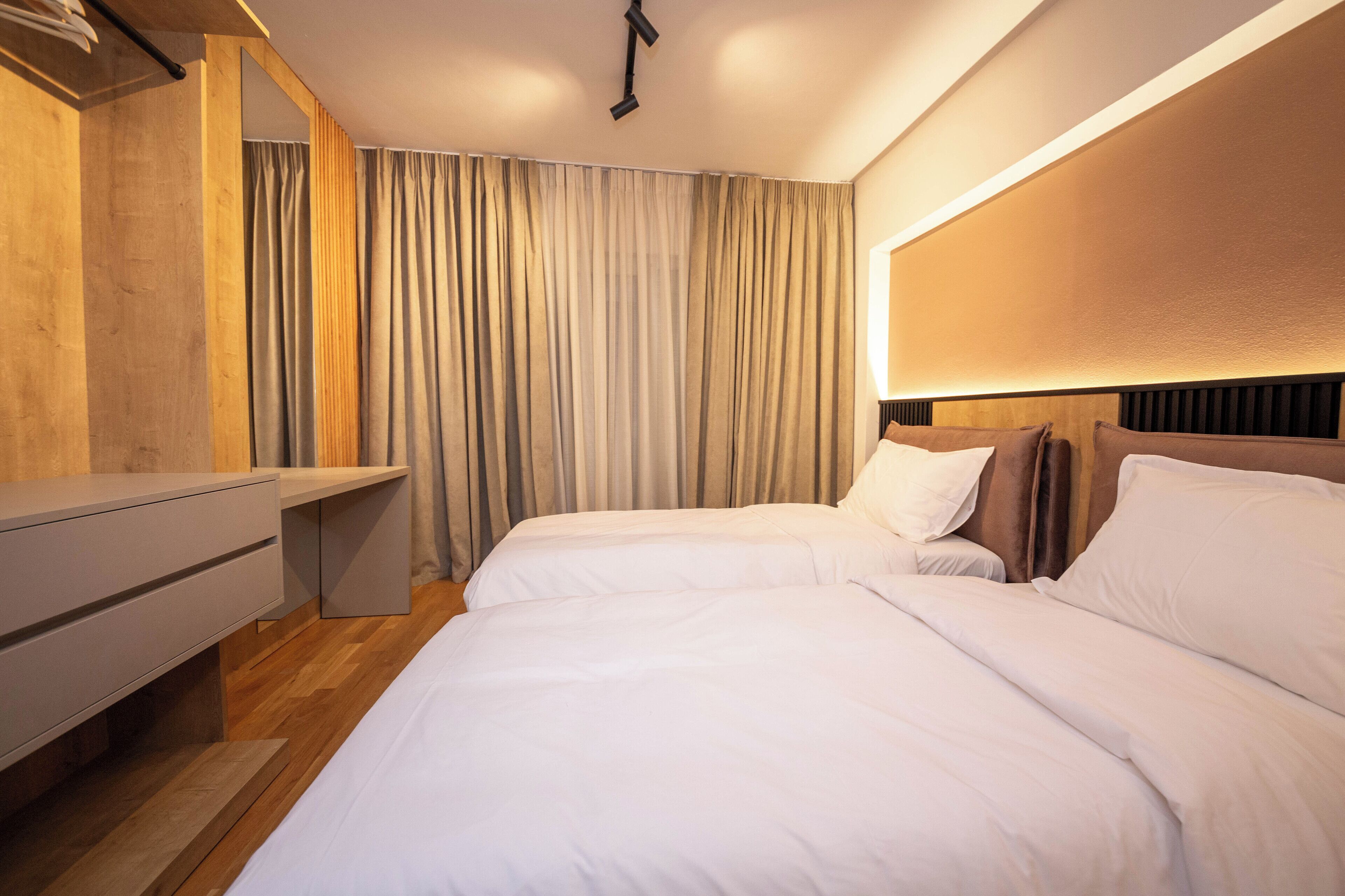 Une chambre d’hôtel avec deux lits, un bureau et une grande fenêtre avec des rideaux.