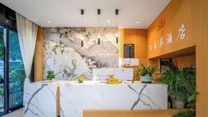 Zona de recepción de hotel con un mostrador de mármol, un panel de pared de madera y un letrero con caracteres chinos.