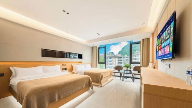 Habitación de hotel con dos camas, un escritorio, un televisor y vistas a edificios.