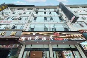 Fachada de hotel con varios letreros, incluyendo un restaurante destacado y un número de contacto.