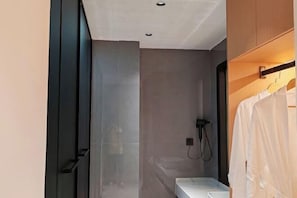 A modern bathroom with a glass shower enclosure, a white sink, and a towel rack.
