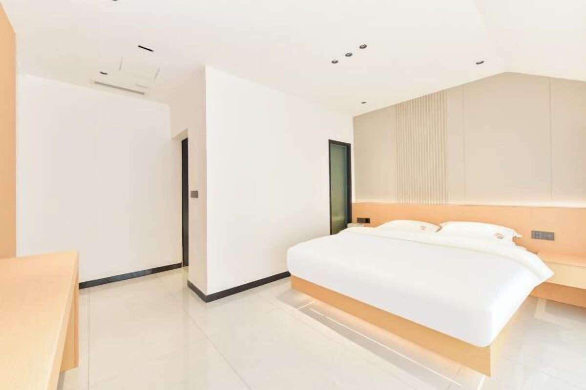 Un dormitorio moderno con una cama grande, una mesita de noche y un televisor montado en la pared.