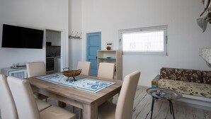 A dining area with a wooden table, chairs, and a TV mounted on the wall. - Casa dell'Asfodelo by Wonderful Italy (Budoni)