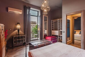 A modern bedroom with a large bed, a wardrobe, a vanity, and a window with a view of a building and greenery. - Ursino apartment with balcony by Wonderful Italy (Catania)