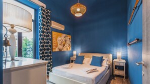 A bedroom with a bed, bedside tables, a lamp, and a wall-mounted air conditioner. - Ursino apartment with balcony by Wonderful Italy (Catania)