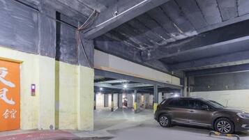 An underground parking garage with multiple levels, concrete walls, and a few parked cars.