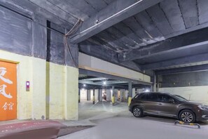 Un parking souterrain à plusieurs niveaux, avec des murs en béton et quelques voitures garées.