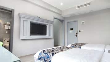 Una camera d'albergo con due letti, una TV montata a parete, una porta con serratura e un piccolo tavolo.