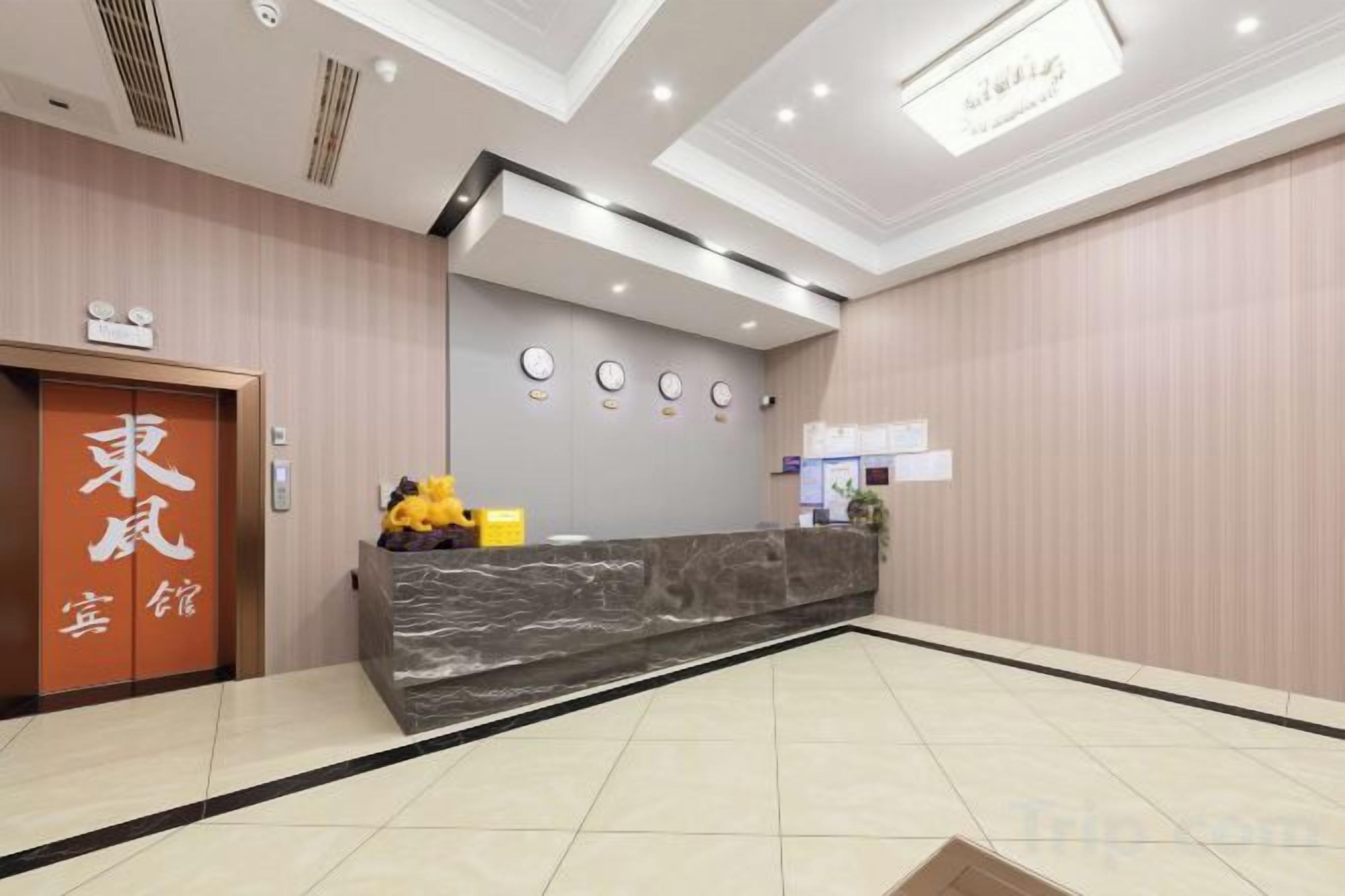 Zona de recepción de un hotel, con mostrador de recepción, una puerta con un letrero y una pared decorada con motivos circulares.