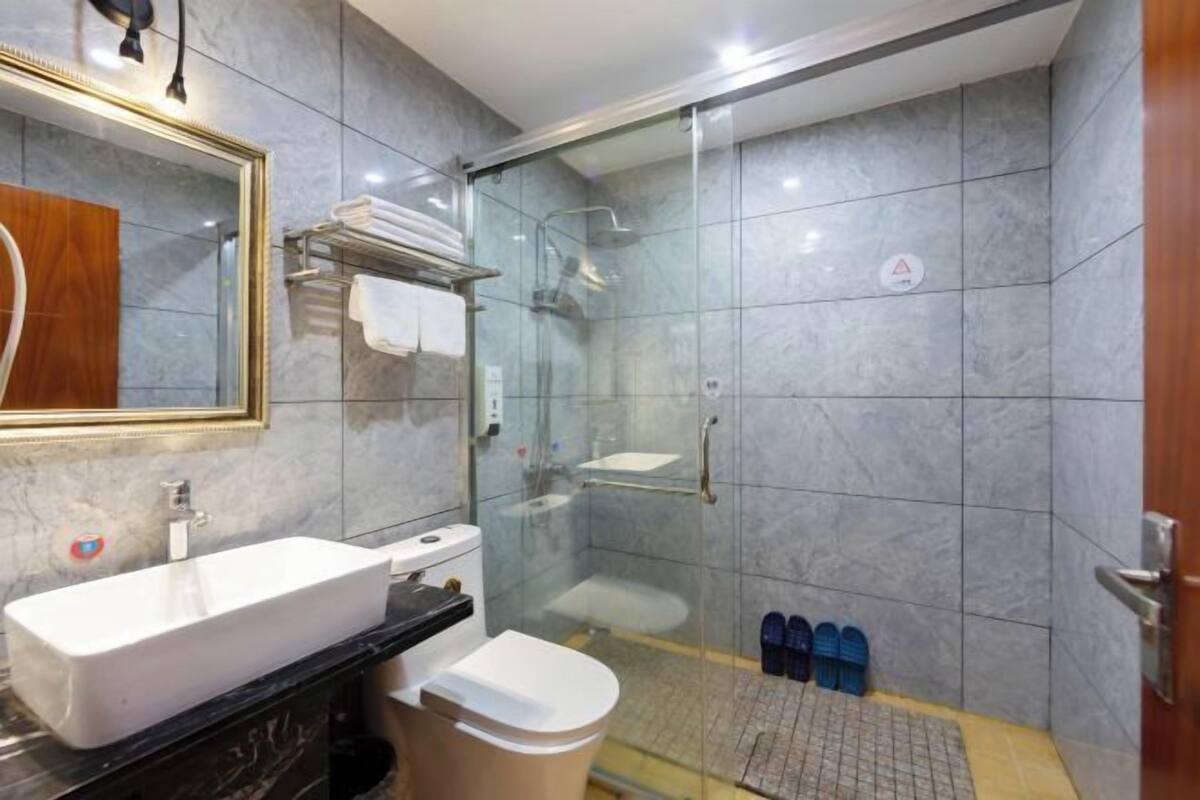 A modern bathroom with a glass-enclosed shower, a sink, and a toilet.