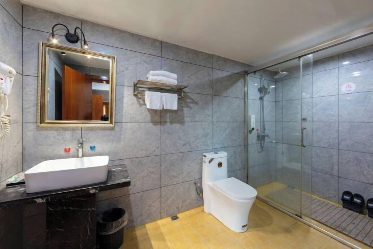 A modern bathroom with a white sink, a toilet, and a glass-enclosed shower.