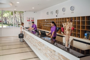 Una zona de recepción con mostrador de piedra, taquillas de madera y relojes en la pared.