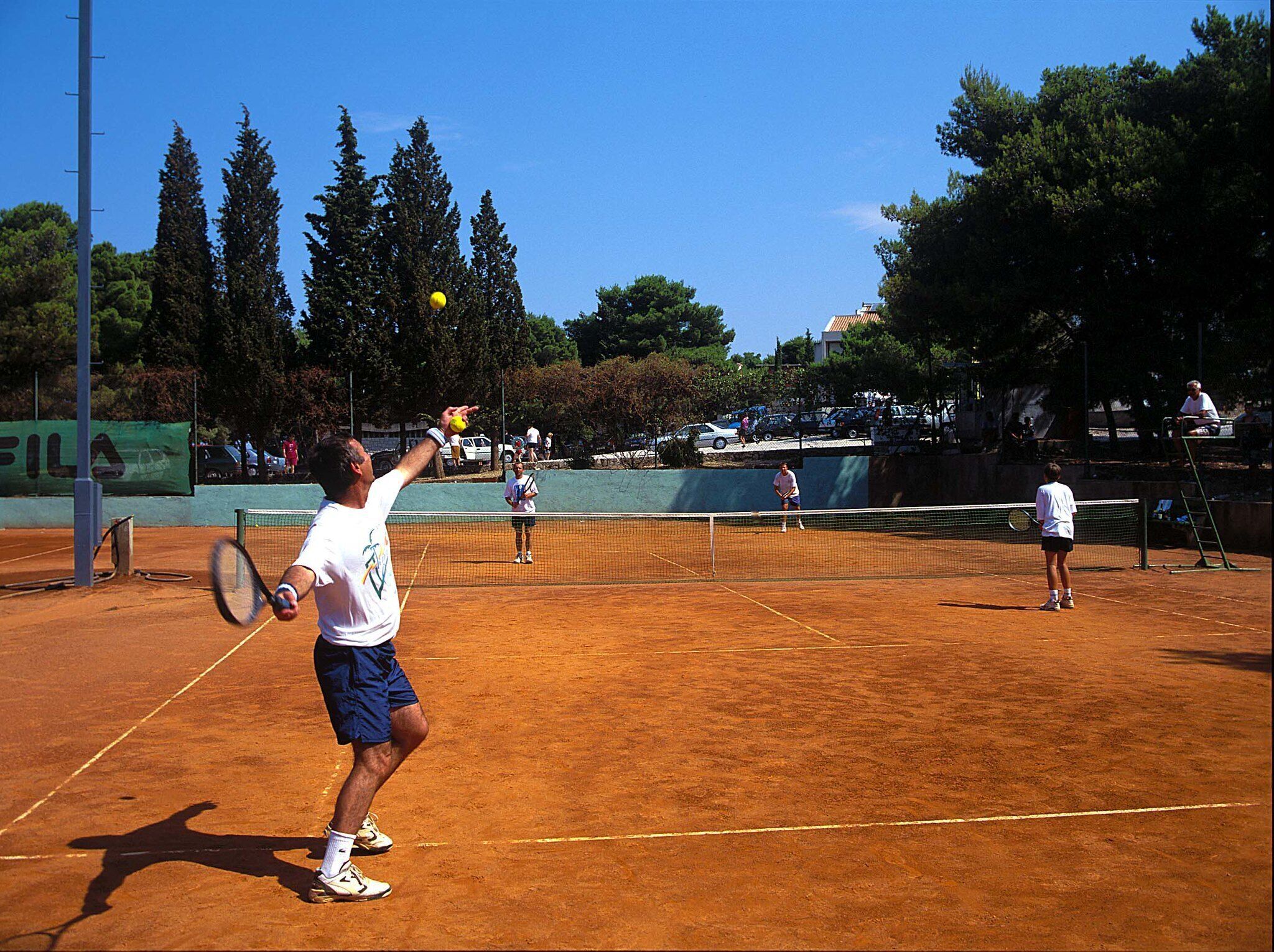 Un court de tennis en terre battue où des joueurs sont en pleine action.