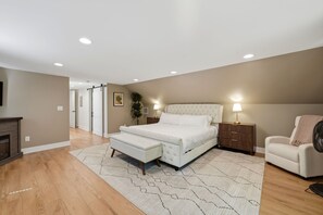 A bedroom with a bed, bedside tables, a chair, a fan, and a fireplace.