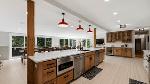 A modern kitchen with wooden cabinets, stainless steel appliances, and pendant lighting.