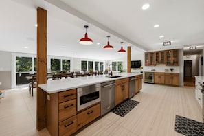 A modern kitchen with wooden cabinets, stainless steel appliances, and pendant lighting. - Hideaway - Pickleball Court, Private Pool, Hot Tub, Sleeps 25! (Michigan City)