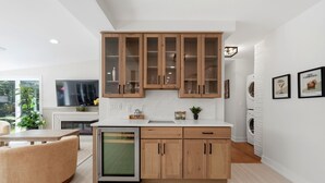 A modern kitchen with wooden cabinets, a built-in dishwasher, and a dining area with a round table and chairs.