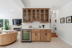 A modern kitchen with wooden cabinets, a built-in dishwasher, and a dining area with a round table and chairs. - Hideaway - Pickleball Court, Private Pool, Hot Tub, Sleeps 25! (Michigan City)