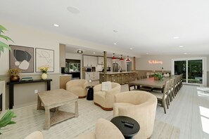A modern living room with a dining area, kitchen, and large windows.