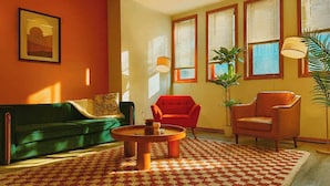 A living room with a green sofa, a red armchair, a wooden coffee table, and a patterned rug.