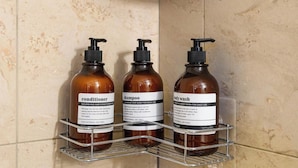 A bathroom with three bottles of hair care products on a metal shelf.