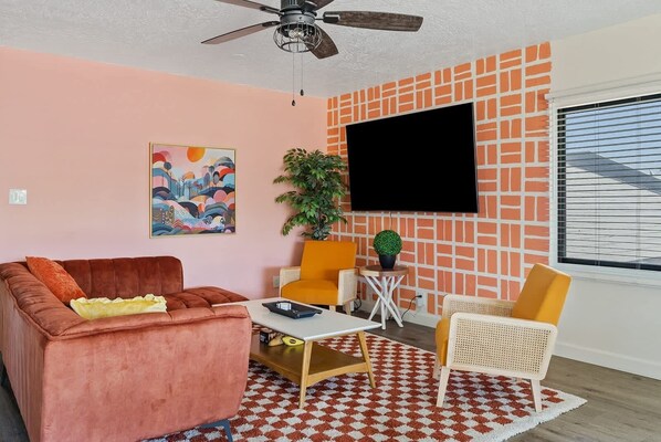 Un salon comprenant un canapé, des fauteuils, une table basse, un téléviseur et un tapis à motifs.