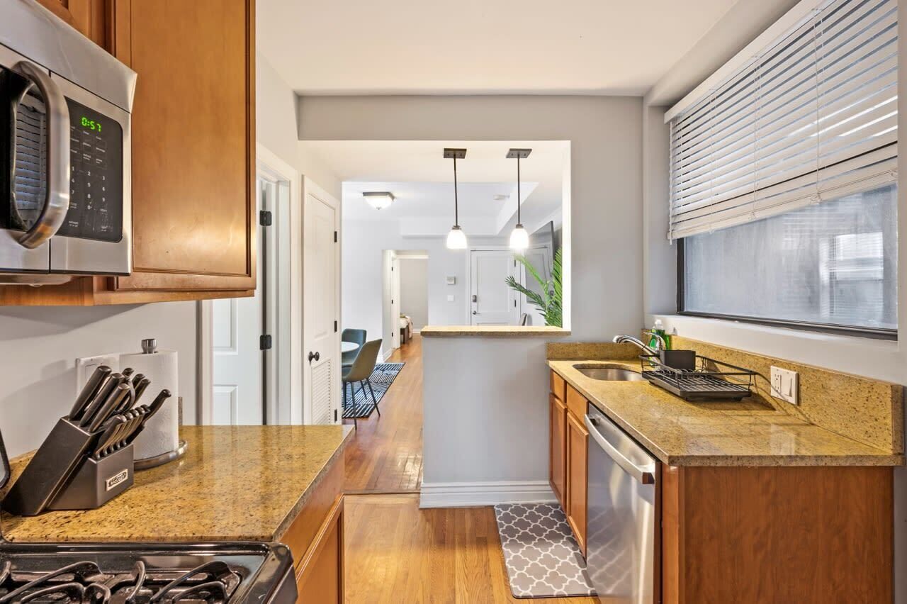 A modern kitchen with a microwave, knife block, and stainless steel appliances.