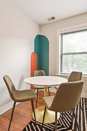 A dining area with a round table, four chairs, and a patterned rug.
