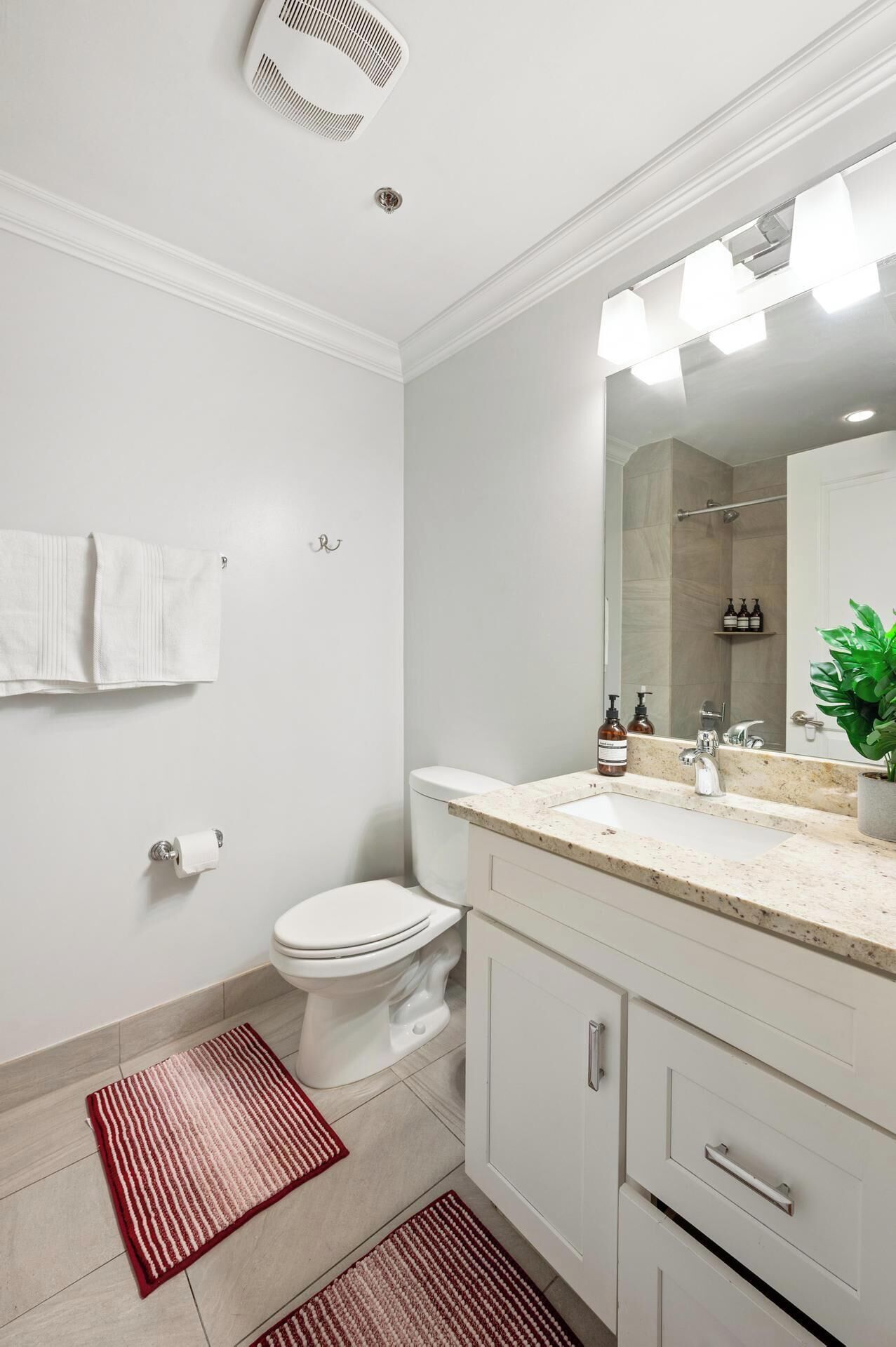 Une salle de bain moderne équipée de toilettes, d’un lavabo, d’un miroir et d’un espace douche.