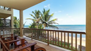 Une terrasse en bois avec des bancs donnant sur une plage et l’océan.