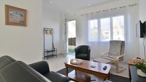 Un salon moderne avec un canapé, une table basse en bois, un fauteuil et un téléviseur.