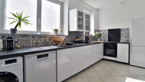 Une cuisine moderne avec des meubles blancs, un four encastré et un lave-vaisselle.