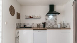 Una cocina con lavavajillas, campana extractora negra, azulejos decorativos en la salpicadura y encimera de madera.