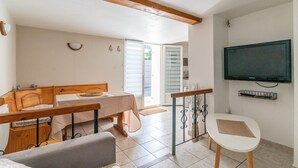 Una habitación con una mesa de comedor, un sofá, un televisor montado en la pared y un ventanal corredizo que da al exterior.