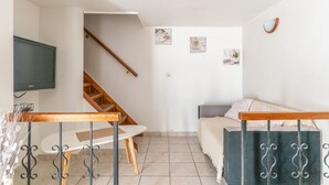 Una sala de estar con sofá, televisor, escalera y mesa de comedor.