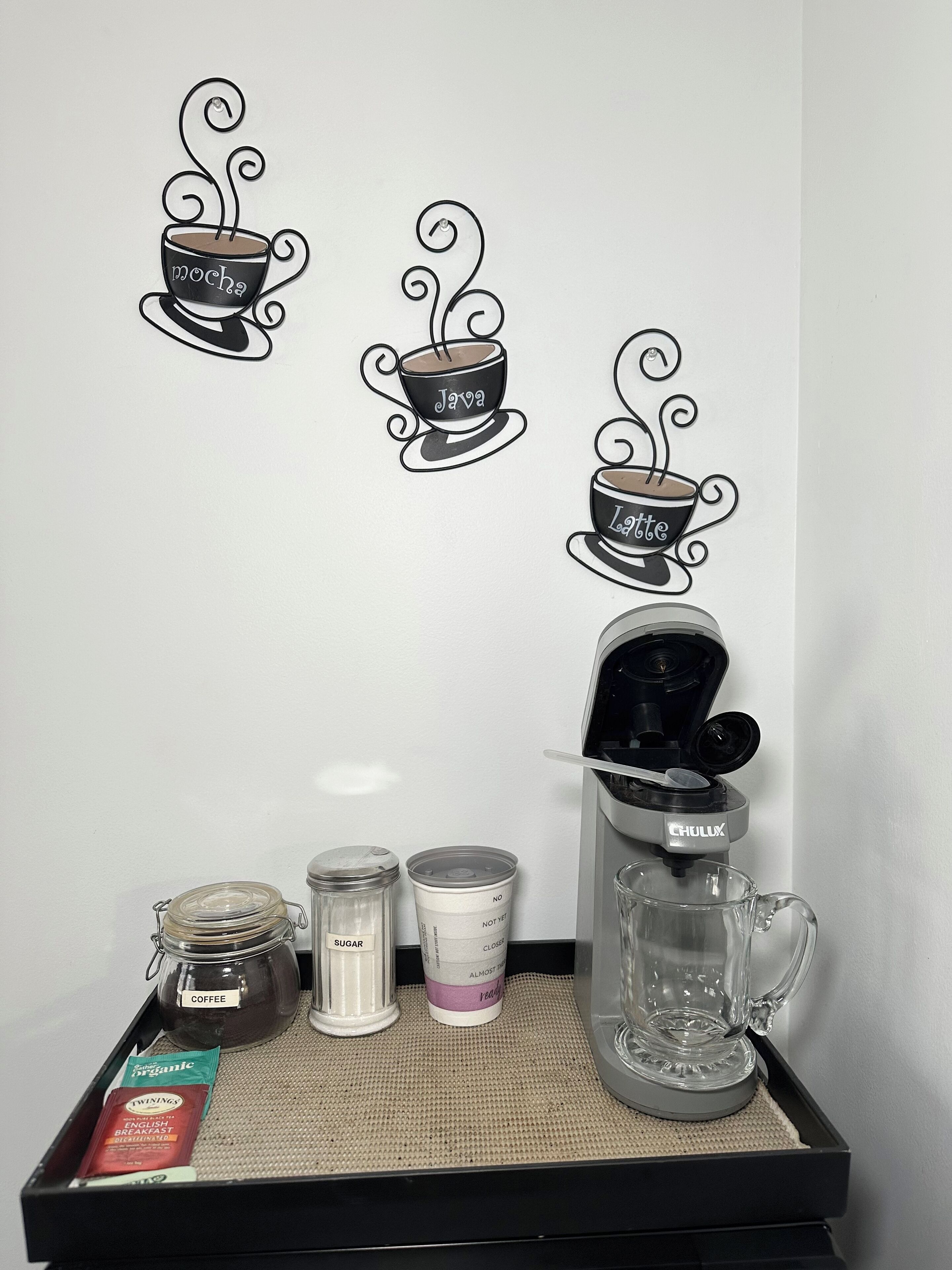 A coffee station with a coffee maker, sugar, creamer, and coffee packets.
