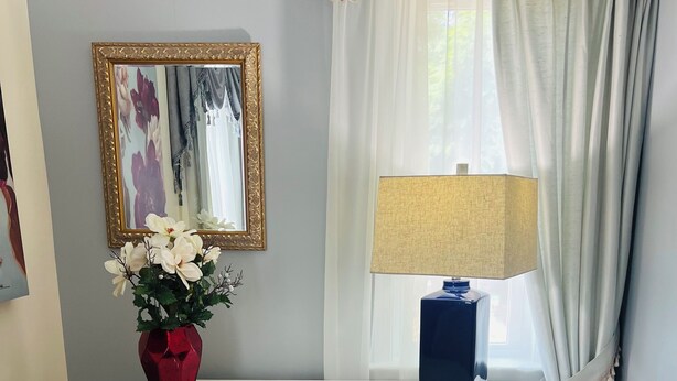 A white desk with a lamp, a chair, and a vase with flowers.