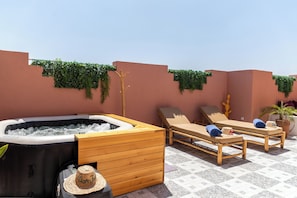 A rooftop terrace with a hot tub, lounge chairs, and a wooden cabinet. -  Riad Dar JuMa Marrakech Suites:Jacuzzi - Piscine & Spa (Marrakech)
