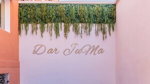 Een zwembadgedeelte met ligstoelen, een betegelde vloer en een muur met beplanting en de tekst 'Dar Tio Ma'.