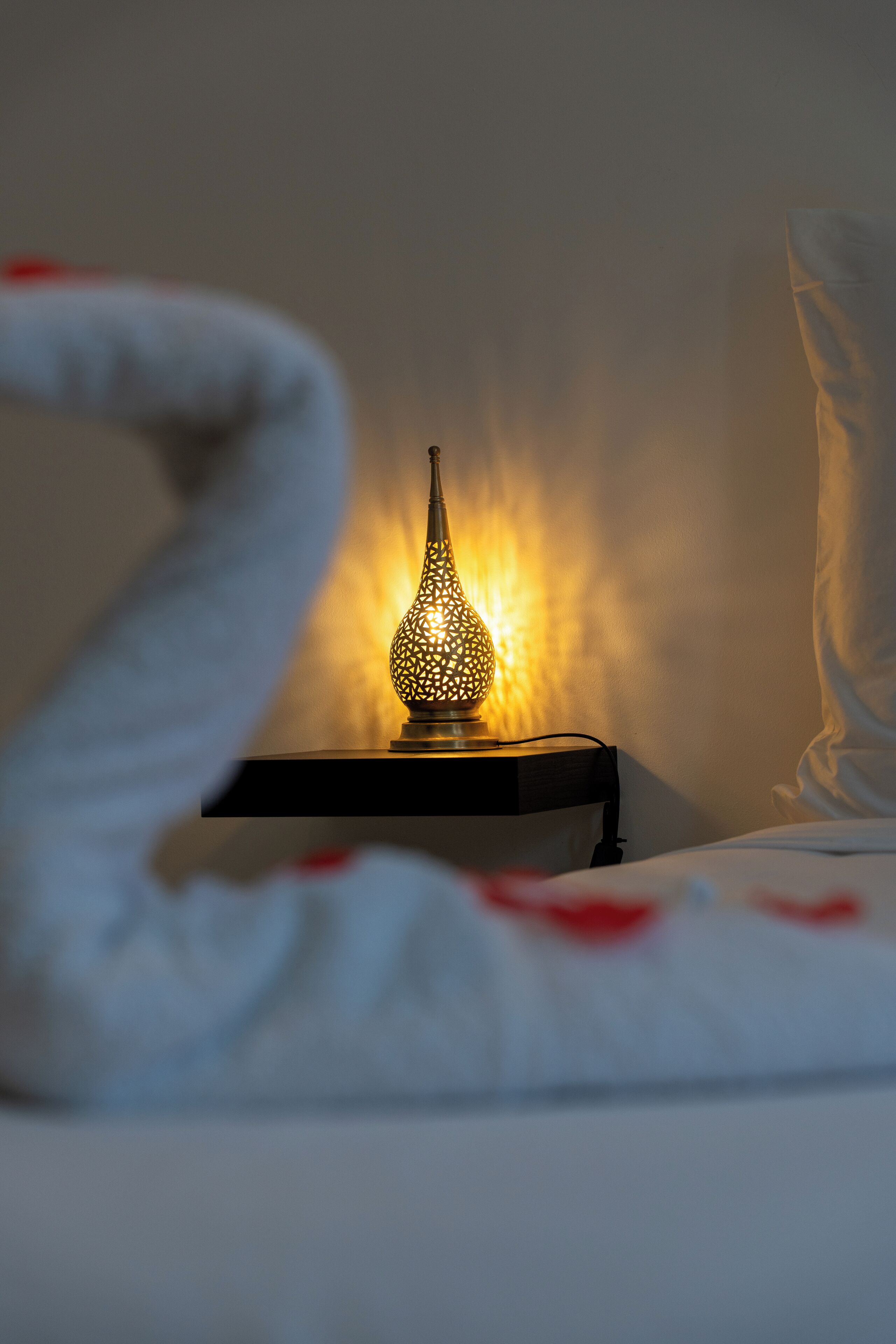 A bed with a decorative lamp on a bedside table.