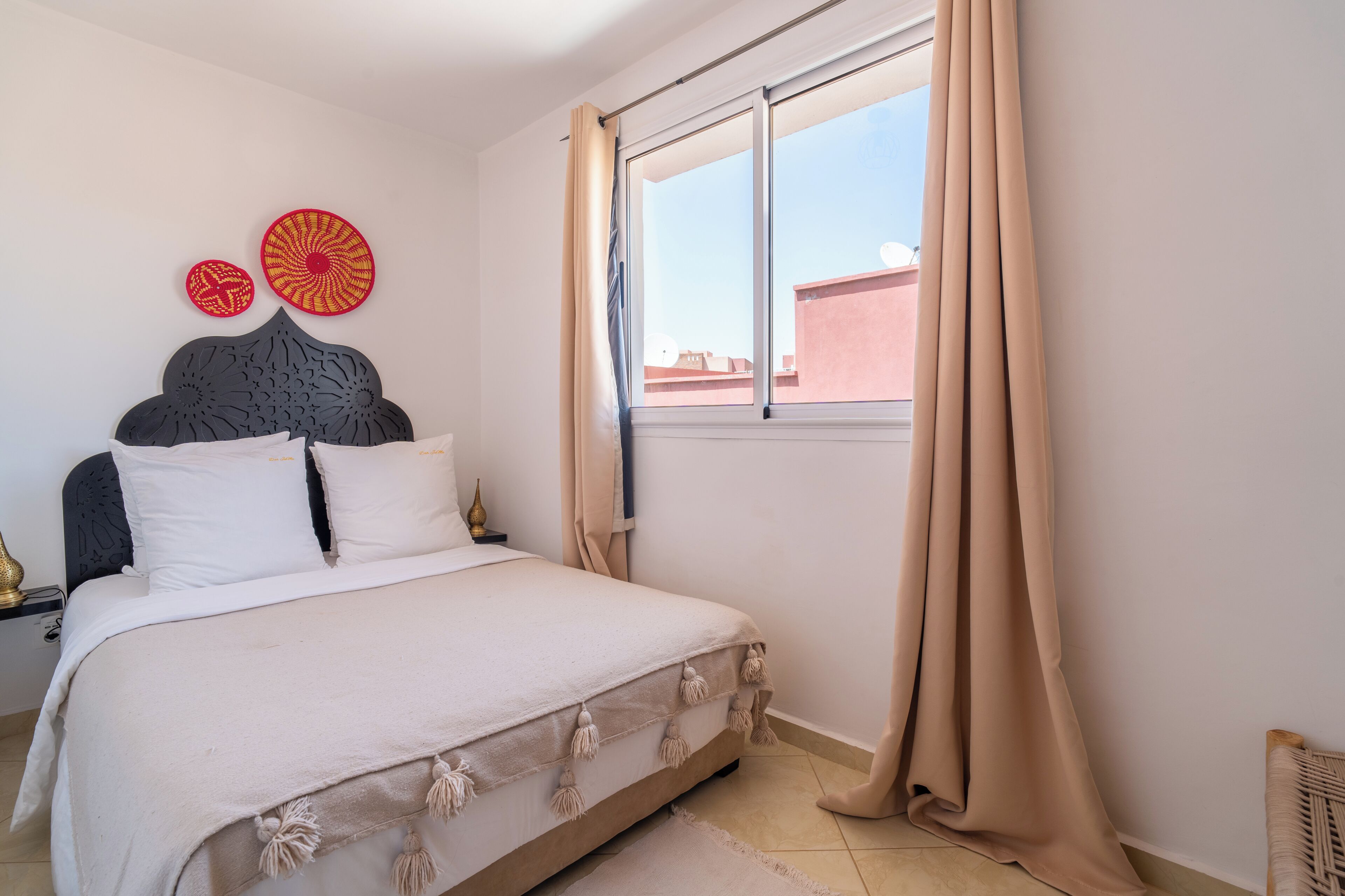 A bedroom with a bed, curtains, a window, and wall decorations.