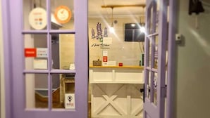 Une porte violette qui donne sur une pièce avec un comptoir blanc et une horloge au mur.