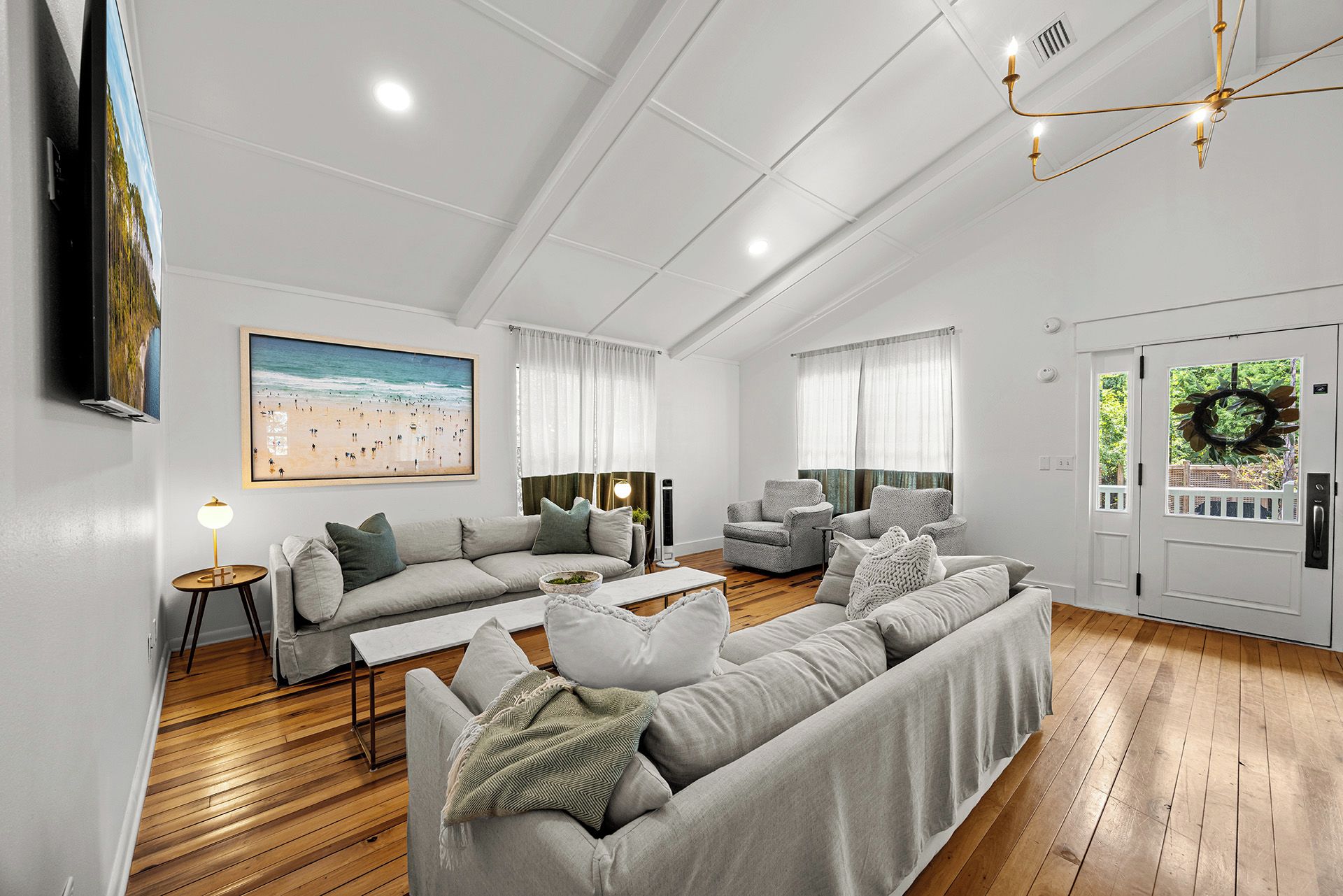 A modern living room with a large sofa, a coffee table, and a television mounted on the wall.