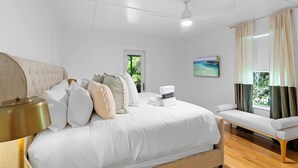 A bedroom with a bed, a bench, a ceiling fan, a door, and a window with curtains. - Grayton Time - Grayton Beach, Heated Private Pool, Walk to the Beach + Red Bar! (Grayton Beach)