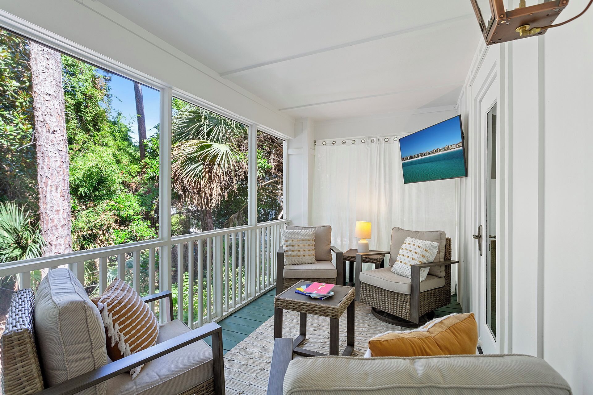 A covered outdoor seating area with wicker furniture, a table, and a view of the outdoors.