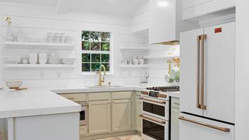 A modern kitchen with white cabinetry, a stainless steel refrigerator, and a gas stove.