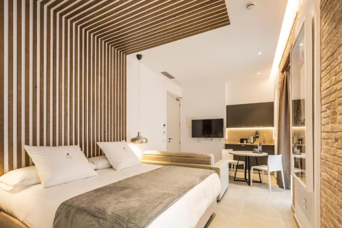 Una habitación de hotel moderna con cama, sofá, zona de comedor y cocina.
