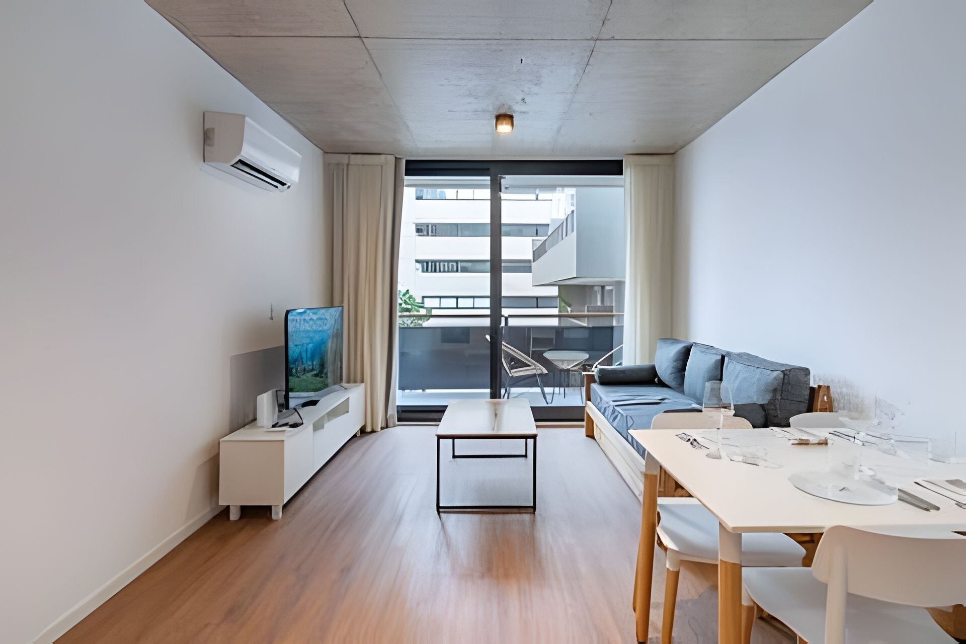 A modern living room with a sofa, a dining table, and a TV.