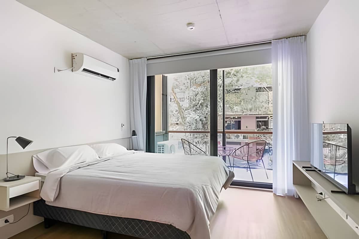 A modern bedroom with a bed, bedside table, and a TV.