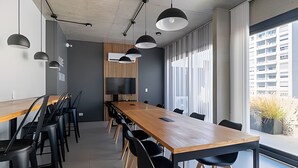 A modern conference room with a long wooden table, black chairs, and pendant lighting. - Urban Rent - Departamentos en el corazon de Belgrano (Buenos Aires)
